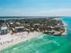Expansive aerial view of turquoise ocean waters meeting a coastline of luxury homes and a sandy beach at 2950 Clark Rd # 113, Sarasota, FL 34231