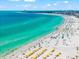 Stunning aerial view of a pristine white sandy beach with aqua ocean and sunbathers with colorful umbrellas at 2950 Clark Rd # 113, Sarasota, FL 34231