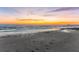 A scenic beach view with calm waves meeting the sandy shore under a vibrant sunset sky at 2950 Clark Rd # 113, Sarasota, FL 34231