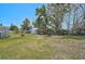 Grassy backyard with scattered trees, a fire pit, and a shed in a serene outdoor setting at 4420 101St W St, Bradenton, FL 34210