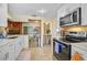 Efficient kitchen with white cabinets, stainless steel appliances, and a view into a unique wood-paneled room at 4420 101St W St, Bradenton, FL 34210