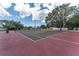 A well-maintained tennis court with a red and green playing surface surrounded by lush trees at 4610 Runabout Way, Bradenton, FL 34203