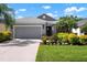 Charming single-story home with a well-manicured lawn, lush landscaping, and a gray two-car garage at 4814 Lake Breeze Ter, Sarasota, FL 34243