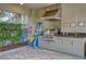 Outdoor kitchen featuring a stainless steel grill, vent hood, sink, and gray cabinetry at 4814 Lake Breeze Ter, Sarasota, FL 34243