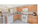 Kitchen featuring oak cabinets, white appliances, and view to living and dining spaces at 4838 San Ortebello Dr, Bradenton, FL 34208