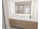 Bright bathroom featuring a wood vanity with marble countertop and illuminated mirror with view to shower at 4950 Remington Dr # 114, Sarasota, FL 34234
