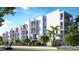 Modern apartment building with a clean white facade and balconies, enhanced by tropical landscaping at 4950 Remington Dr # 114, Sarasota, FL 34234