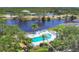 Aerial view of community pool, surrounded by tropical landscaping and a serene lake at 623 Estuary Dr, Bradenton, FL 34209