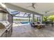 The outdoor living space boasts a barbecue, comfortable seating, and a view of the screened-in pool and lake at 6252 Winding Pine Dr, Nokomis, FL 34275