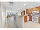 Modern kitchen with wooden cabinets, granite countertops, and a breakfast bar looking into the living room at 6460 Mourning Dove Dr # 102, Bradenton, FL 34210