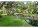 Pond featuring lush grassy banks, tall trees, and plants, creating a serene outdoor space at 6460 Mourning Dove Dr # 102, Bradenton, FL 34210