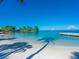 Beautiful white sand beach with crystal clear turquoise water and a view of a dock at 7 Sandy Cove Rd, Sarasota, FL 34242