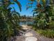A stone path through tropical foliage that leads to a serene lake with lush vegetation in the distance at 7 Sandy Cove Rd # 9B, Sarasota, FL 34242
