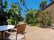 A covered patio with neutral furniture offers a relaxing spot amidst lush landscaping and tropical foliage at 7 Sandy Cove Rd, Sarasota, FL 34242