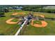 Aerial view of multiple baseball fields with green grass, clay, a small building, and tall lights at 7168 Chatum Light Run, Bradenton, FL 34212