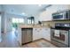Open kitchen with stainless steel appliances, white cabinets, and a view into the dining room at 7168 Chatum Light Run, Bradenton, FL 34212
