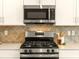 Modern kitchen featuring stainless steel appliances, white cabinets, and stylish backsplash at 7425 Divot Loop, Lakewood Ranch, FL 34202