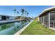 Waterfront backyard with lush grass and palm trees along a tranquil canal at 780 Jungle Queen Way, Longboat Key, FL 34228
