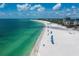 Breathtaking aerial view of a pristine beach with blue umbrellas, turquoise water, and beachfront condos at 800 S Blvd Of The Presidents # 19, Sarasota, FL 34236