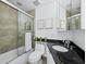 Bathroom features dark granite counter with a sink and mirror and glass enclosed tub at 800 S Blvd Of The Presidents # 19, Sarasota, FL 34236
