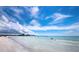 Clear, shallow water on a sandy beach meets a skyline under a bright blue sky with fluffy white clouds at 800 S Blvd Of The Presidents # 19, Sarasota, FL 34236
