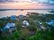 Panoramic aerial view of waterfront home nestled among lush trees, showcasing serene surroundings at sunset at 8871 Fishermens Bay Dr, Sarasota, FL 34231