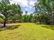 Expansive backyard featuring a lush lawn and mature trees, offering plenty of space for outdoor activities at 8871 Fishermens Bay Dr, Sarasota, FL 34231