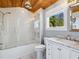 A charming bathroom with a glass-enclosed shower and tub, featuring a wood-paneled ceiling at 8871 Fishermens Bay Dr, Sarasota, FL 34231