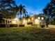 Inviting backyard view of this home featuring lush landscaping and stylish architecture at twilight at 8871 Fishermens Bay Dr, Sarasota, FL 34231