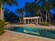 Backyard pool with a poolside pergola, lush greenery, and a tranquil setting for relaxation and enjoyment at 8871 Fishermens Bay Dr, Sarasota, FL 34231