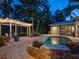 Beautiful backyard pool area with a pergola, string lights, brick patio, and lush tropical landscaping at 8871 Fishermens Bay Dr, Sarasota, FL 34231