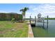 Waterfront property featuring a private dock with a boat lift, palm trees, and serene views at 10432 Sandpiper W Rd, Bradenton, FL 34209