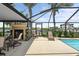 Screened in patio with fireplace, seating area, and view of the canal and pool at 10432 Sandpiper W Rd, Bradenton, FL 34209