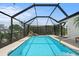 Sparkling pool inside screened enclosure with waterfall feature and lush landscaping at 10432 Sandpiper W Rd, Bradenton, FL 34209