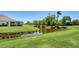 Backyard featuring a tranquil pond with lush green grass and tropical landscaping at 1203 Calle Grand St, Bradenton, FL 34209