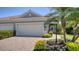 Front exterior of a home with a paver driveway, a three-car garage, and tropical landscaping at 1203 Calle Grand St, Bradenton, FL 34209
