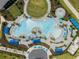 Aerial view of a resort-style pool with blue umbrellas, palm trees, and lounge chairs at 12440 Wellen Golf St # 105, Venice, FL 34293