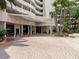 Well-maintained building entrance with brick pavers, palm trees, seating and a covered awning at 1255 N Gulfstream Ave # 402, Sarasota, FL 34236