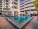 Community pool surrounded by lounge chairs, palm trees, and condominium buildings at 1255 N Gulfstream Ave # 402, Sarasota, FL 34236