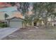 Inviting single-story home featuring a two-car garage, well-manicured lawn, and lush trees at 12805 Raysbrook Dr, Riverview, FL 33569