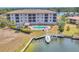 Beautiful condo building in waterfront community with boat dock, boat, grass, landscaping, and community pool nearby at 1349 Aqui Esta Dr # 143, Punta Gorda, FL 33950