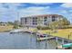Beautiful condo building in waterfront community with boat dock, boat, grass, landscaping, and community pool nearby at 1349 Aqui Esta Dr # 143, Punta Gorda, FL 33950