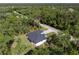 Aerial view of modern home nestled in a lush, green, wooded landscape with a gravel driveway at 14009 Daniels Ave, Port Charlotte, FL 33953