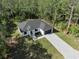 Aerial view of a modern home with a paved driveway, set in a green landscape with mature trees at 14009 Daniels Ave, Port Charlotte, FL 33953