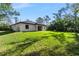 Spacious backyard with green grass and modern home featuring a covered patio, perfect for outdoor enjoyment at 14009 Daniels Ave, Port Charlotte, FL 33953