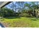 Expansive backyard featuring lush green grass and mature trees offering privacy and a serene outdoor space at 14009 Daniels Ave, Port Charlotte, FL 33953