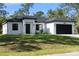 Charming one-story home with a paved driveway, a well-manicured lawn, and a black garage door at 14009 Daniels Ave, Port Charlotte, FL 33953