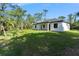 Lush backyard view of a modern home featuring a well-maintained lawn and mature trees for privacy at 14009 Daniels Ave, Port Charlotte, FL 33953