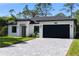 Charming one-story home with a paved driveway, a well-manicured lawn and a black garage door at 14009 Daniels Ave, Port Charlotte, FL 33953