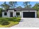 Charming one-story home with a paved driveway, a well-manicured lawn and a black garage door at 14009 Daniels Ave, Port Charlotte, FL 33953